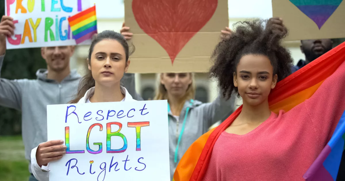 Group of people on the street holding signs protesting for LGBTQ rights