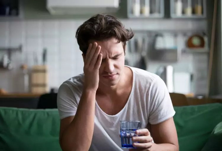 Young Man Suffering From Strong Fatigue Sitting With Glass Of Water
